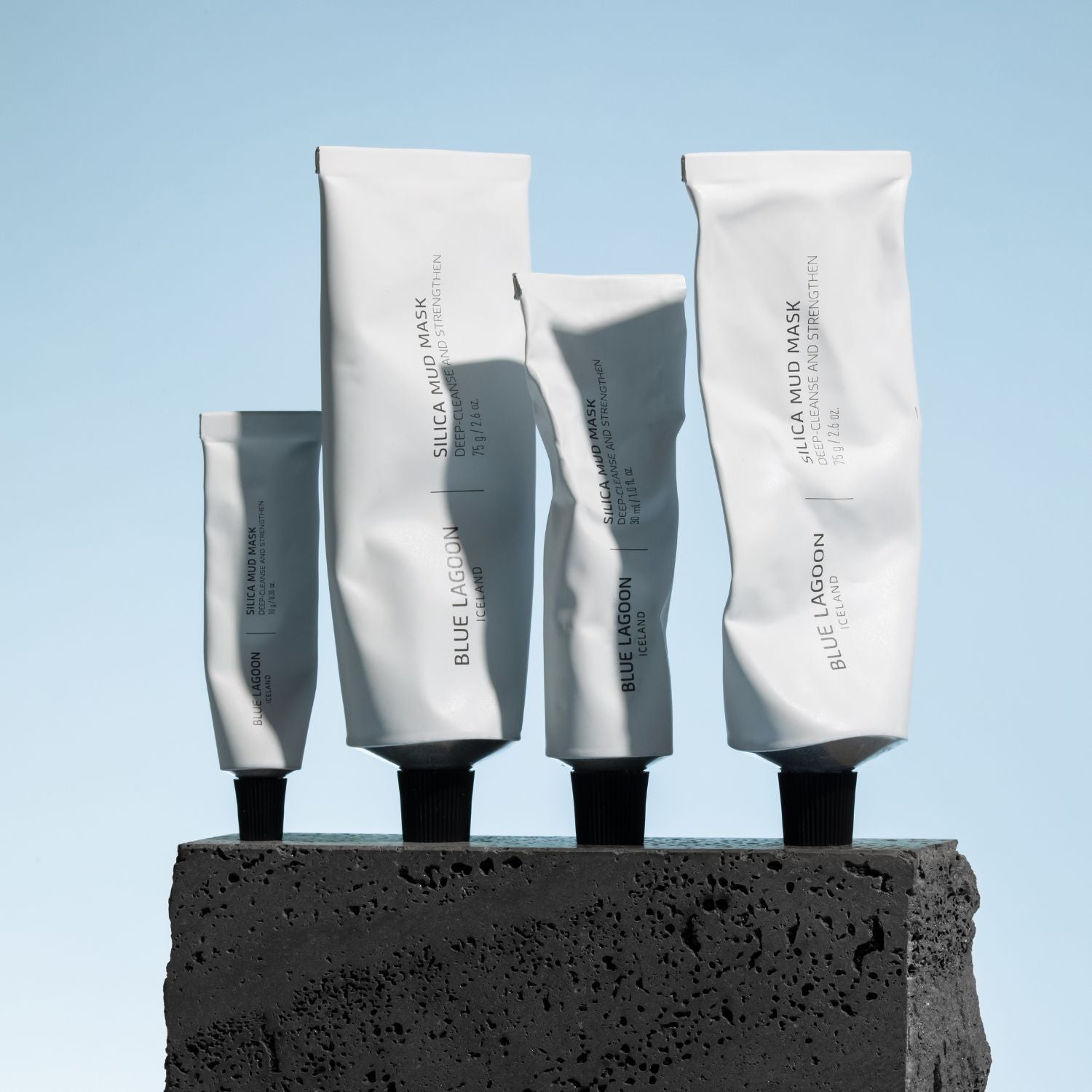 Silica Mud Mask túpur ofan á stein með bláum bakgrunn