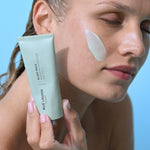 Fyrirsæta með Lava Algae Mask borið á kinn og heldur á túpunni